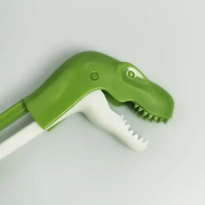 Green plastic dinosaur-shaped toothbrush with white bristles featuring sharp teeth for kids training dino chopsticks decorbites