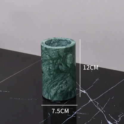 A cylindrical green marble candle holder with polished surface and natural veining from a green marble bathroom set