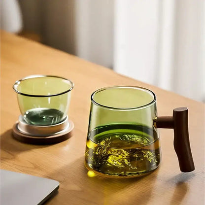 Translucent green glass teapot with dark wood handle filled with golden tea leaves in decorbites glass tea cup set