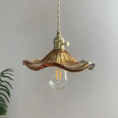 A delicate amber glass pendant light with fluted design and polished copper hardware for dining room use