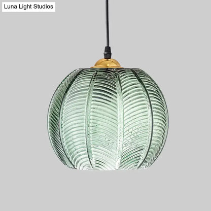Green ribbed glass pendant lamp with translucent pumpkin shape and brass fixture for dining room lighting