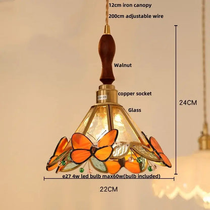 Green stained glass butterfly pendant light with warm orange amber tones brass accents wooden walnut canopy decorbites clear glass