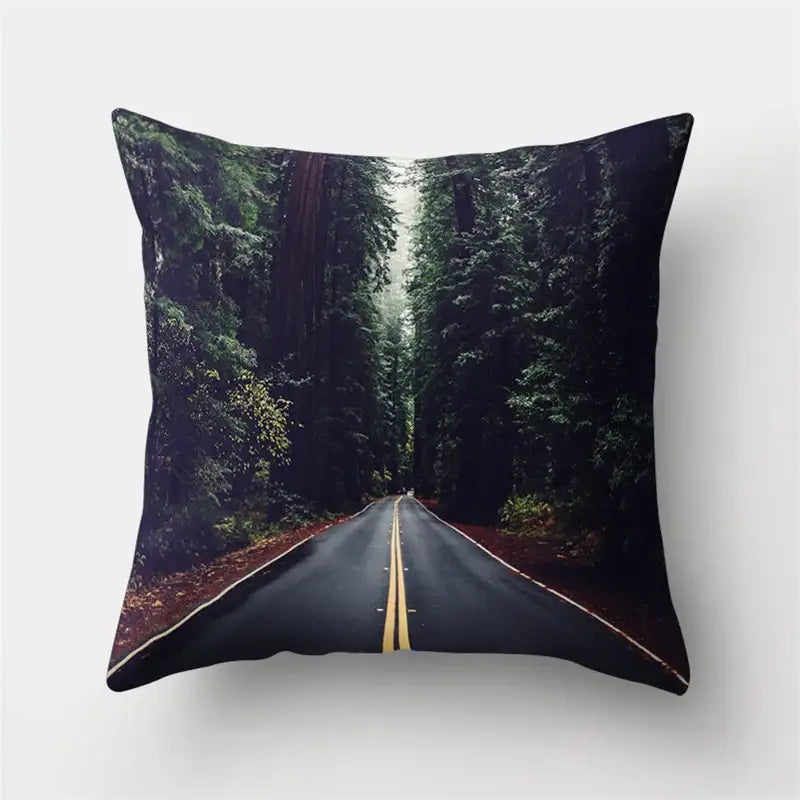 Square throw pillow with green tropical leaves forest print featuring a winding road and dense evergreen trees decorbites green tropical decor