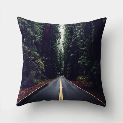 Square throw pillow with green tropical leaves forest print featuring a winding road and dense evergreen trees decorbites green tropical decor