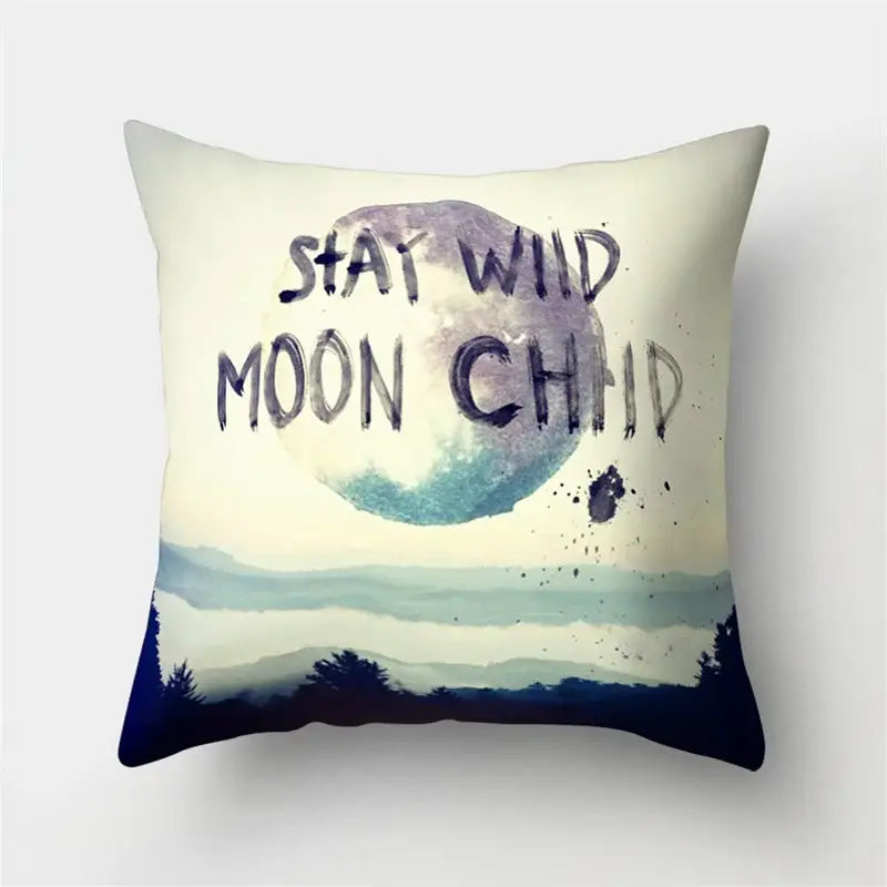 Cream-colored throw pillow with watercolor moon mountain design and stay wild moon child text for decorbites green tropical leaves forest decor