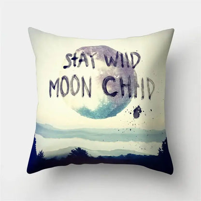 Cream-colored throw pillow with watercolor moon mountain design and stay wild moon child text for decorbites green tropical leaves forest decor