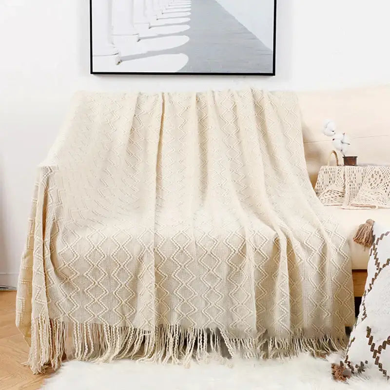 Cream-colored knitted throw blanket with diamond pattern and tassels featured in decorbites grey nordic waffle knit decor