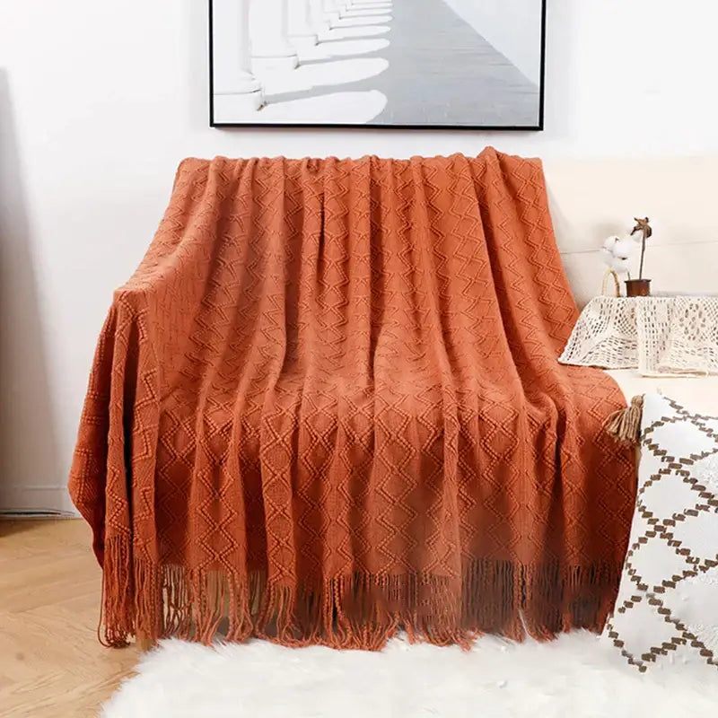 Warm terracotta knitted throw blanket with diamond pattern and tassels complementing decorbites grey nordic waffle knit decor