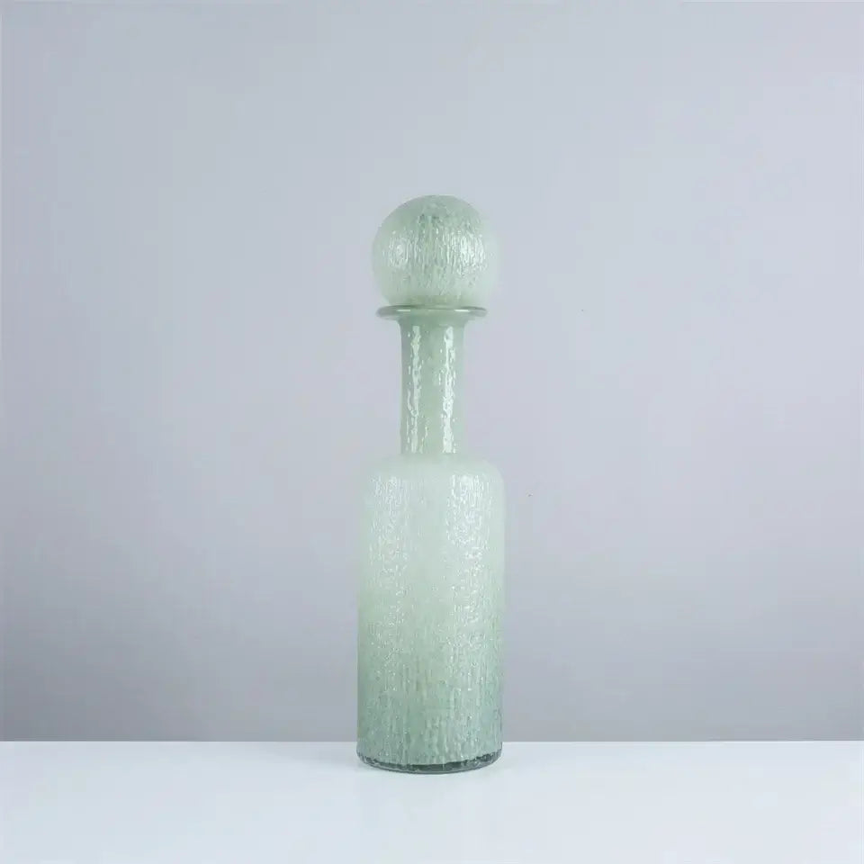 A frosted green glass decanter with a textured bubble surface and hammer lid stopper in decorbites grey round glass style