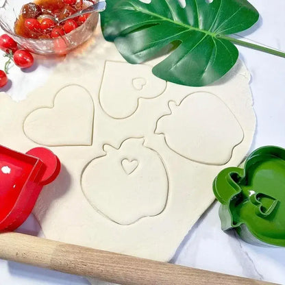Red plastic heart-shaped hand pie mold with handle beside a green mold in a halloween hand pie molds set