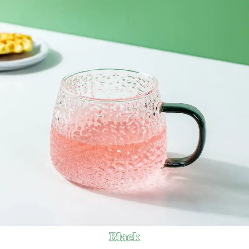 Textured 400ml hammer pattern glass mug with black handle filled with pink liquid kitchen glassware