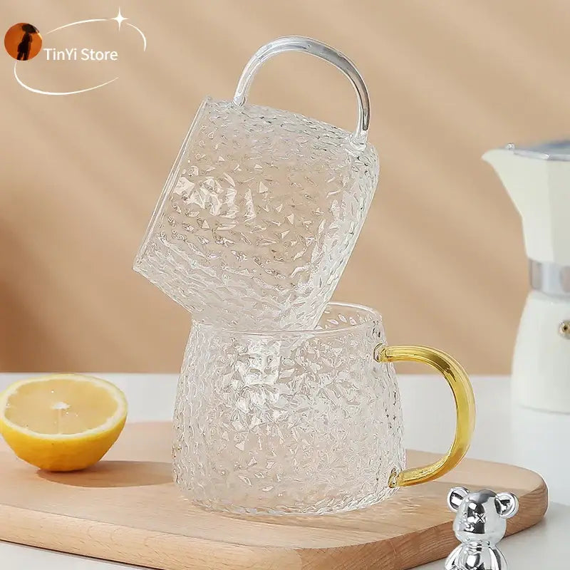 Hammered clear glass water cup with textured finish and gold-tone handle ideal for kitchen use