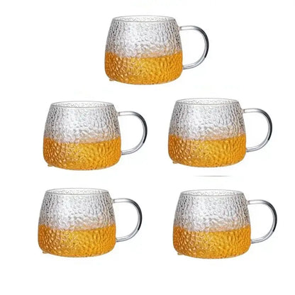 Set of five hammered clear glass water cups with amber lower halves and gold handles for kitchen use