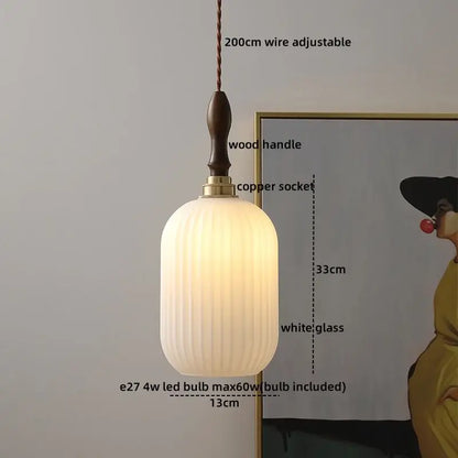 A warm glowing pendant lamp with white ribbed glass shade, dark wood handle, and brass socket for living room lighting