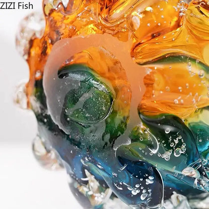Vibrant hand blown glass fish sculpture with swirling orange green and blue hues complements colorful flower edge vase