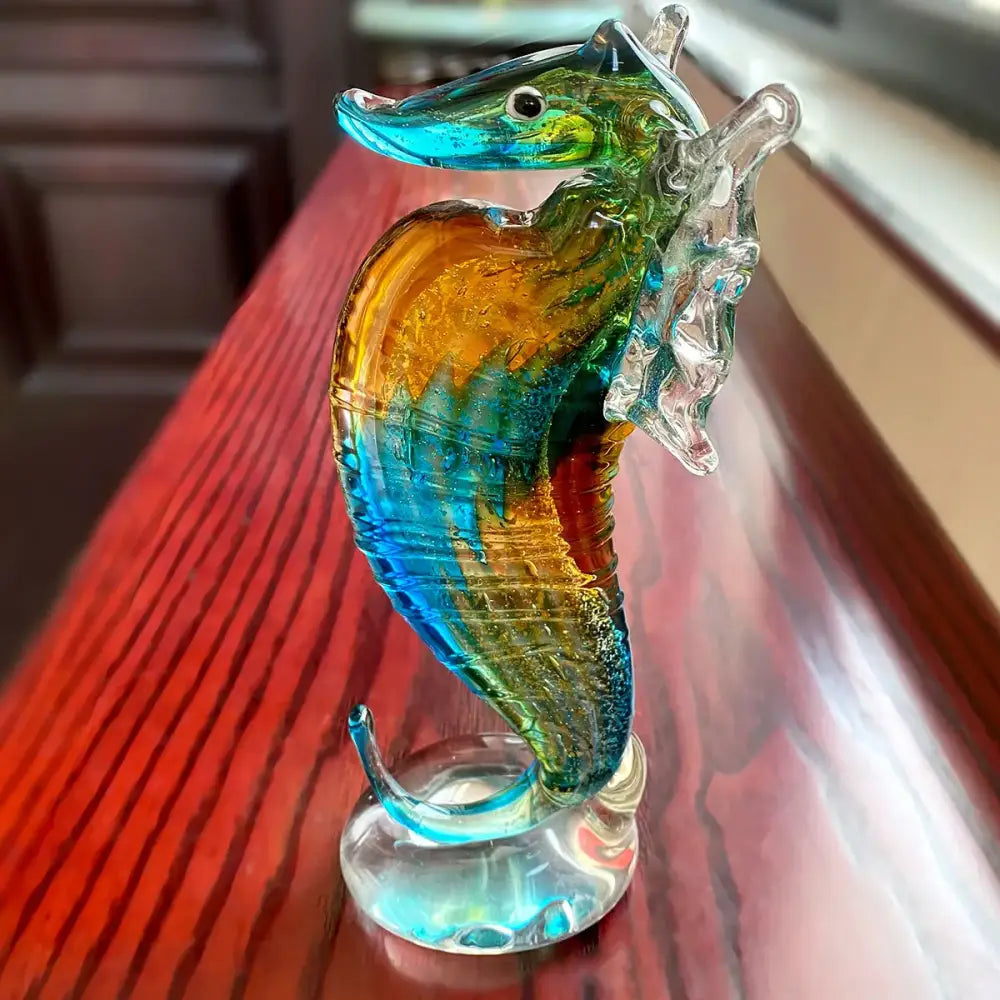 Hand blown glass seahorse figurine with translucent turquoise, amber, and emerald green body for living room decor