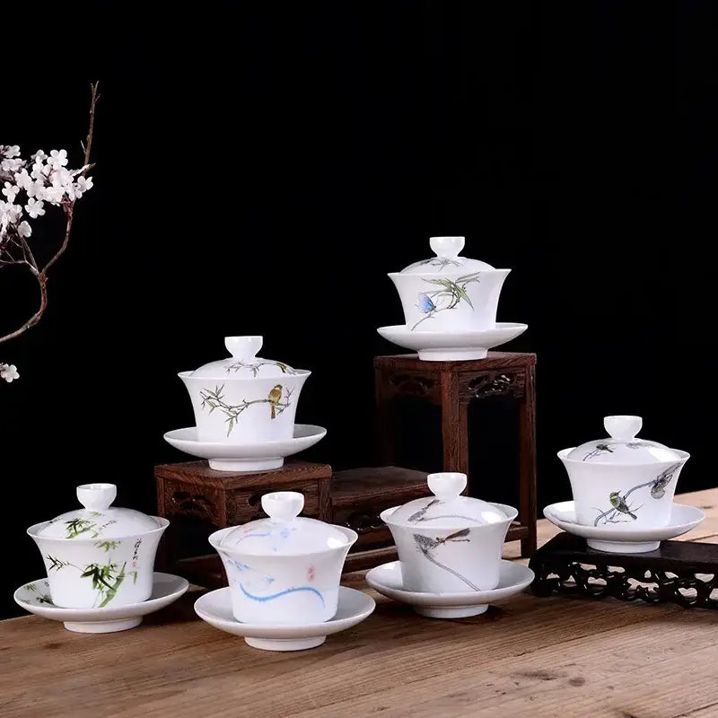 White porcelain gaiwan tea set with hand-painted bird and bamboo designs including lid, base, and matching saucer