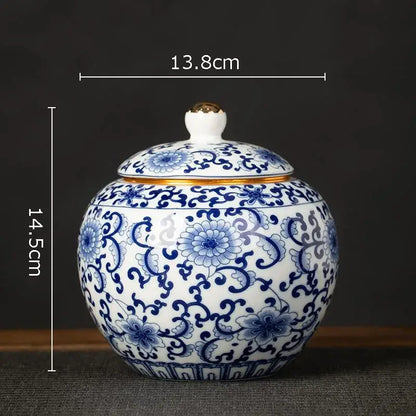 A hand-painted white porcelain tea canister with intricate blue floral patterns and a gold-trimmed lid for kitchen storage