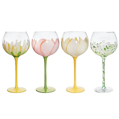 Set of four hand painted glass goblets with pink and yellow floral designs on clear glass and colorful stems