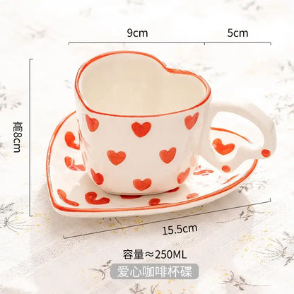 White ceramic love mug with hand painted heart handle and red polka dots on saucer set for kitchen use