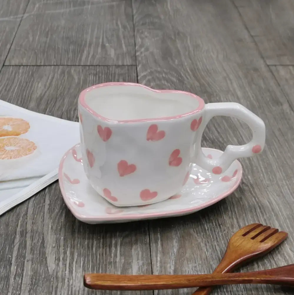 A white ceramic love mug with hand painted heart handle and pink polka dots with matching kitchen saucer set