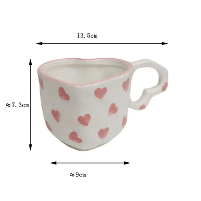 A white ceramic love mug with a hand painted heart handle and pink painted hearts with matching saucer set