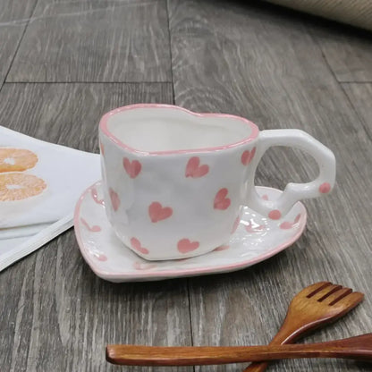 A white ceramic love mug with hand painted heart handle and pink polka dots with matching saucer set