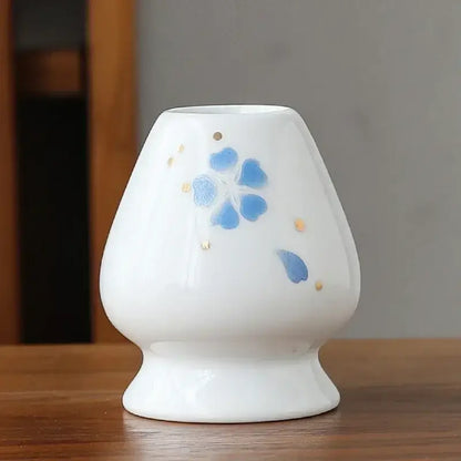 Hand painted white ceramic matcha whisk holder stand with blue floral design and gold accents as a whisk holder