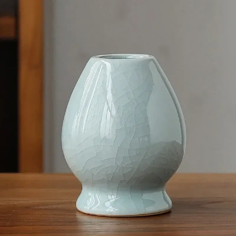Delicate light blue ceramic matcha whisk holder stand with crackled glaze and rounded bulbous shape for whisk storage