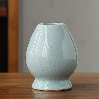 Delicate light blue ceramic matcha whisk holder stand with crackled glaze and rounded bulbous shape for whisk storage