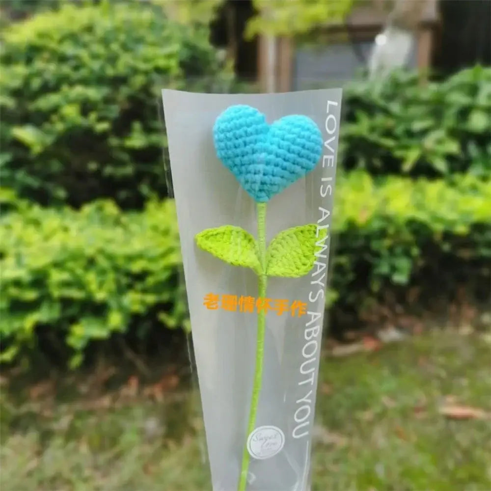 Hand woven love heart yarn crochet flower bouquet with blue heart and green leaves in clear plastic sleeve for decor