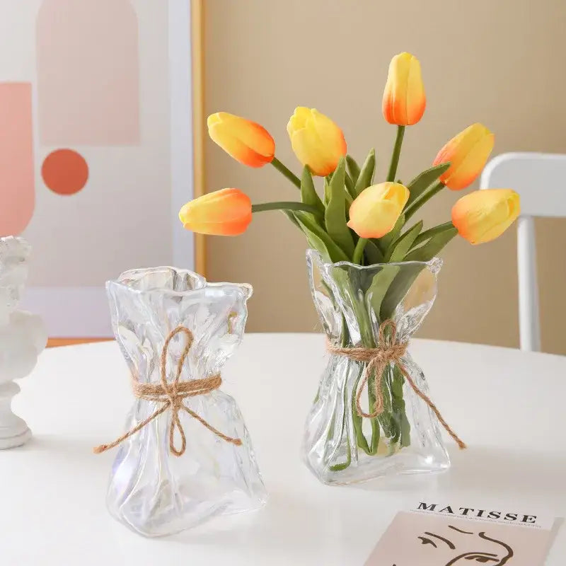 Handcrafted clear glass folded road vase set with textured glass and twine ties holding yellow and orange tulips decorbites clear glass