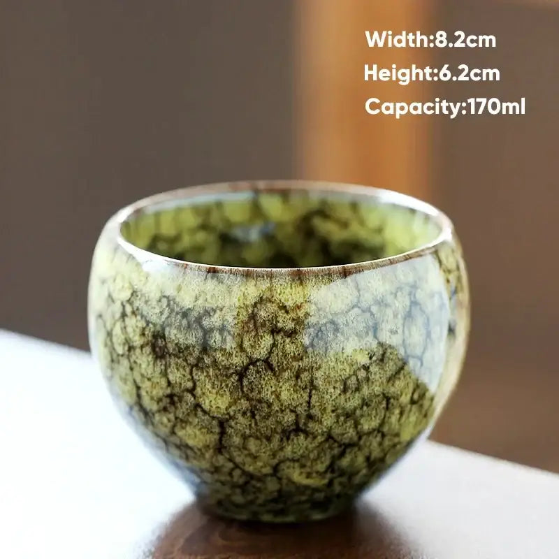 Handcrafted ceramic coffee cup with crackled green and brown glaze and organic textured surface for dining room use