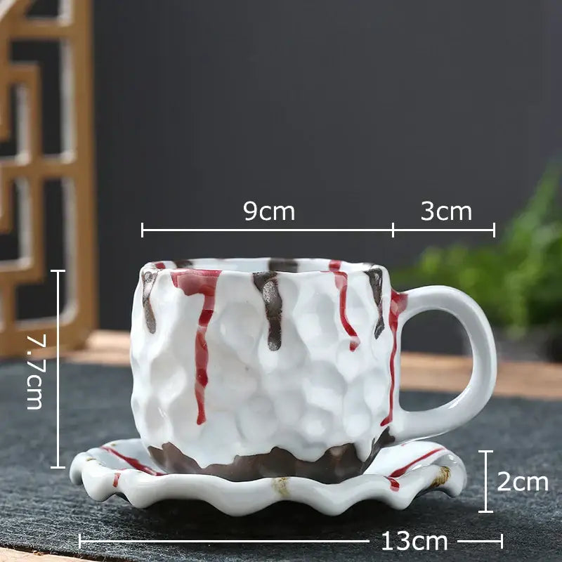 White ceramic hammer pattern porcelain mug with textured surface and red brown drips on matching scalloped saucer