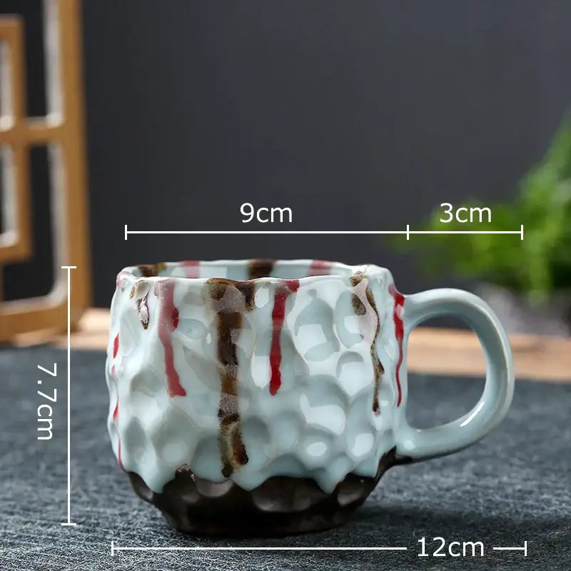 A textured light blue hammered porcelain mug with red and brown drips, part of a kitchen set of 2 pattern porcelain mugs