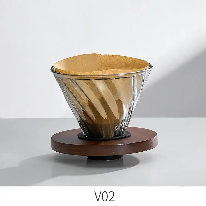 Handcrafted decorbites glass coffee brewer with ribbed twisted design and brown paper filter on dark wooden base