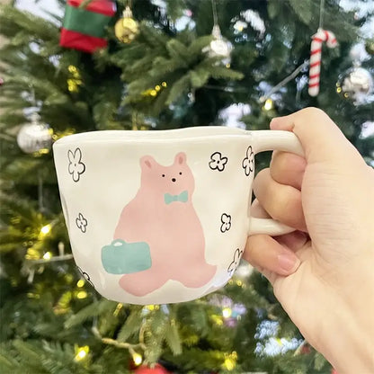 Handcrafted white ceramic bear mug featuring a pink bear with a bow tie and suitcase surrounded by black flowers