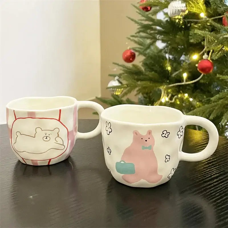 Handcrafted white ceramic bear mug set featuring a pink bear with suitcase and a white bear lounging striped bag