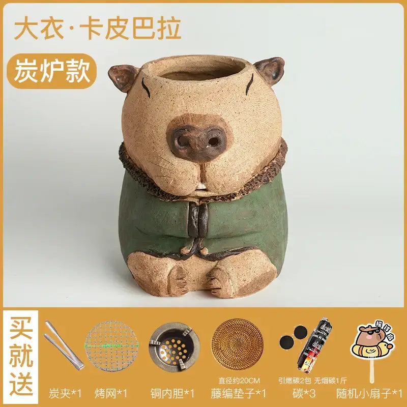 A charming beige ceramic handmade capybara carbon oven surrounding stove tea warmer with green robe and fur trim