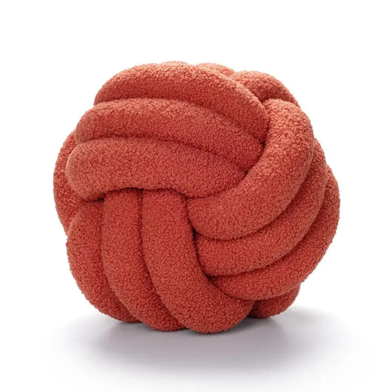A plush coral-colored handmade knotted boucle circle throw pillow made of soft textured fabric for bedroom decor
