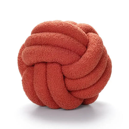 A plush coral-colored handmade knotted boucle circle throw pillow made of soft textured fabric for bedroom decor