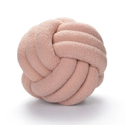 A handmade dusty rose-colored knotted boucle circle plush pillow made of soft textured fleece for bedroom decor