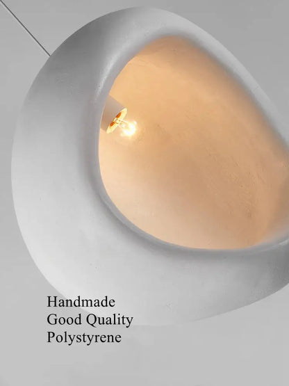 A sleek white ceramic handmade nordic designer chandelier with an organic shape and warm-toned integrated bulb for dining room decor