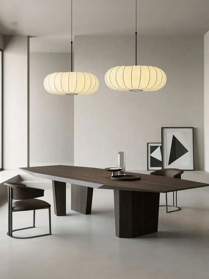 Modern minimalist dining table with dark wood top and geometric legs under a decorbites handmade silk pumpkin pendant light