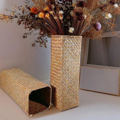 Tall rectangular handmade woven straw vase filled with dried flowers in warm earthy tones for home decoration