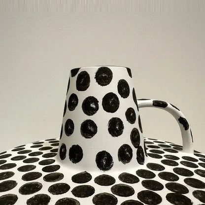 White ceramic mug with bold black white dots and matching handle on coordinating dotted decorbites black white surface