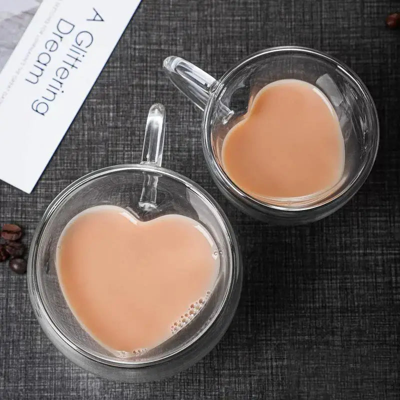 Heart glass mug set featuring double-walled clear glass mugs with heart shapes and clear handles filled with creamy beverage