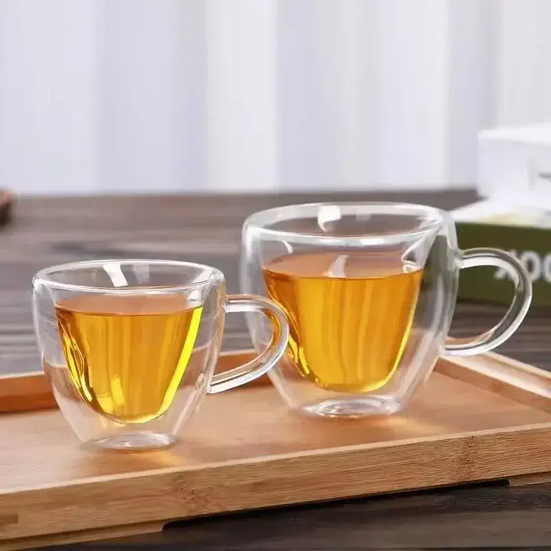 Heart shaped double wall glass mug set with clear double walled glass mugs filled with golden liquid for kitchen use