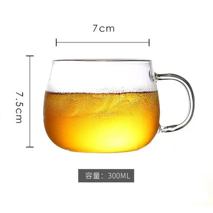 Clear glass mug with handle filled with golden liquid next to a heat resistant glass pitcher water carafe with stainless lid