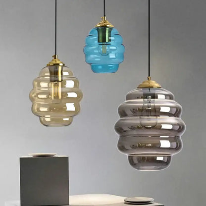Three honeycomb-shaped glass pendant lights with brass accents in amber blue and gray colorful glass decorbites ball design